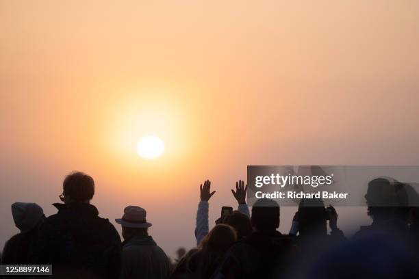 Spiritually-minded revellers celebrate sunrise during the summer Solstice at the ancient late-Neolithic stones of Stonehenge, on 21st June 2023, in...