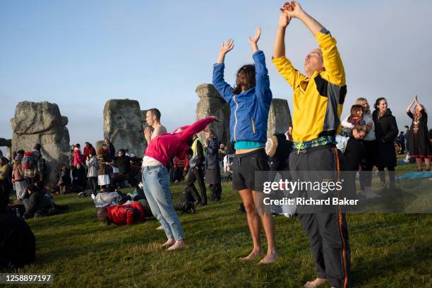 Spiritually-minded revellers celebrate the summer Solstice with a yoga class at the ancient late-Neolithic stones of Stonehenge, on 21st June 2023,...