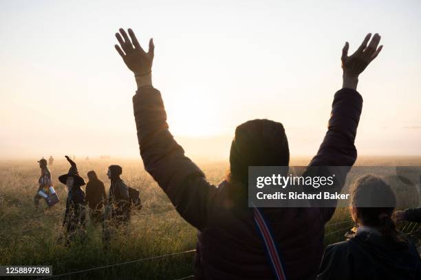 Spiritually-minded revellers celebrate sunrise during the summer Solstice at the ancient late-Neolithic stones of Stonehenge, on 21st June 2023, in...