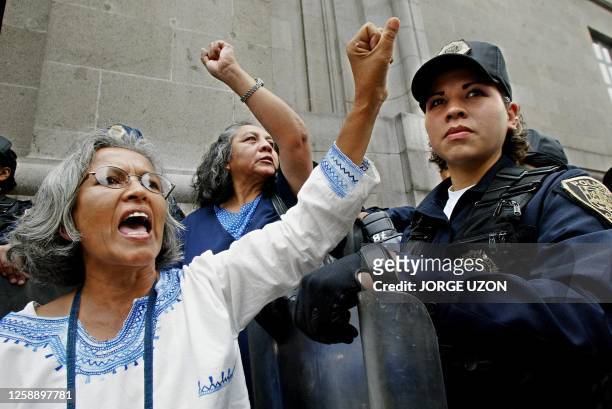 Two women protest next to a police woman along with other indigenous Mexicans outside the Supreme Court in Mexico City 09 September 2002. Indigenous...