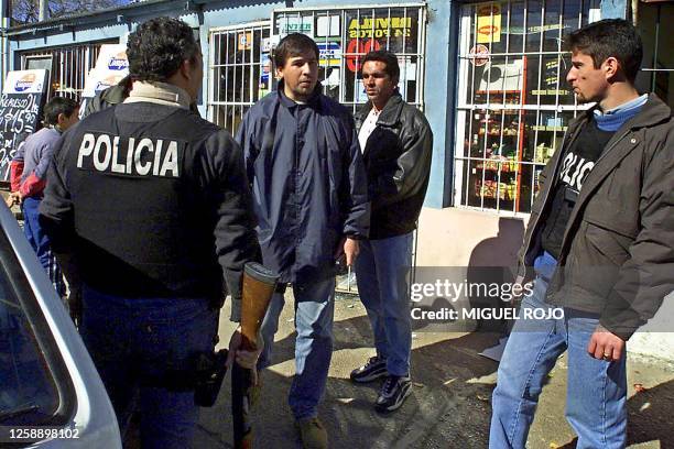 Policemen patrol outside a shopping center in Montevideo that was looted, 02 August 2002. Uruguay continued to be gripped by a financial crisis that...