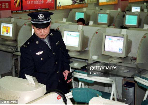 Policeman inspects an Internet cafe in Beijing, 17 June 2002, as authorities launch a tough crackdown on illicit web cafes. Young Chinese will most...