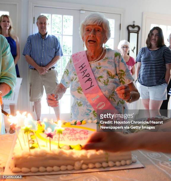 Rose Molkestad watches friends and family light the candles on her birthday cake as she celebrated her 100th birthday at a party at one of her son's...