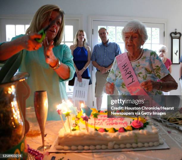 Rose Molkestad watches friends and family light the candles on her birthday cake as she celebrated her 100th birthday at a party at one of her son's...