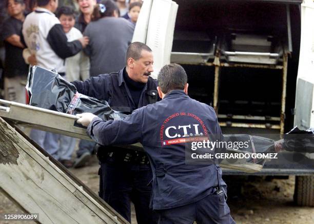 Police members remove the body of one of the three children who died in an accidental explosion from a hand grenade, 18 September 2002. The three...