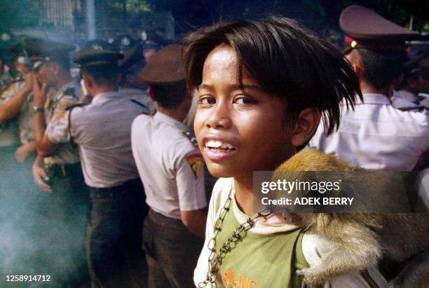 Street child holding a monkey looks on at a protest in front of a police blockade near the president's residence during a demonstration against the...