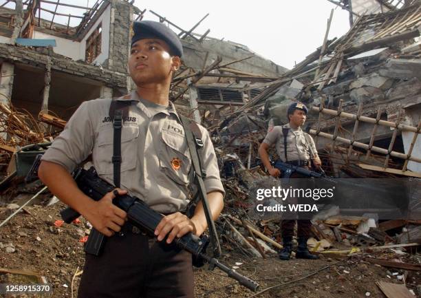 Policemen stand guard at bomb site during a purification ceremony in Kuta, Denpasar Bali, 15 November 2002, one month after a horrific bomb attack...