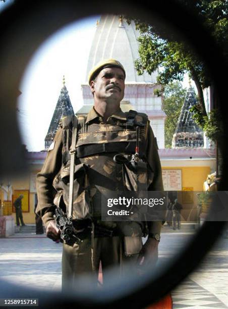 Central Reserve Police Force paramilitary stands guard behind the main gate of the Raghunath temple 28 November 2002 in Jammu. Tight security has...