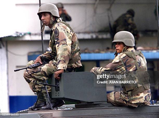 Members of the Venezuelan army seated on an armoured car guard the headquarters of the Metropolitan Police in Caracas 17 November 2002. The President...