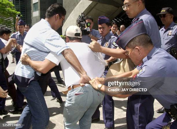 Policemen arrest an anti-Arroyo demonstrator during a rally outside the Philippine Stock Exchange in the suburban Makati financial district 05...