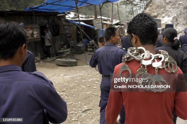 Nepalese plainclothes policeman, carrying empty handcuffs, and uniformed colleagues return from handing over 18 Tibetans who entered Nepal illegally...