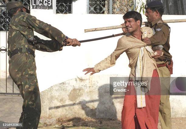 Policeman holds an Hindu priest as an Army personnel beats him up in Bhopal, 23 January 2003 after priests conducting rituals for a 45-day ceremony...