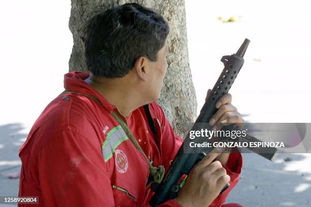 Man armed with a gun takes cover behind a tree as demonstrations turn violent in La Paz, Bolivia 12 February 2003. Un hombre armado con una...