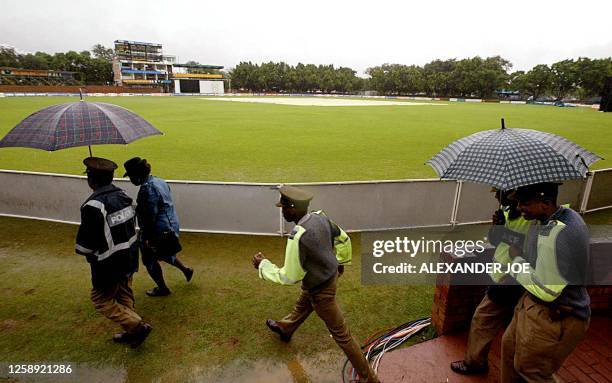 Zimbabwean police guard Bulawayo Queens Club while taking cover from the rain 22 February 2003 where the World Cup Cricket match between Australia...