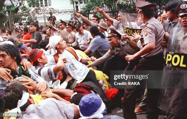 Indonesian students lean down as policemen push back during demonstration near by residence of Indonesia's President Megawati Sukarnoputri in Jakarta...