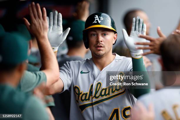 Ryan Noda of the Oakland Athletics celebrates in the dugout after hitting a three-run home run off Gavin Williams of the Cleveland Guardians during...