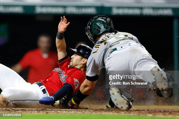 Steven Kwan of the Cleveland Guardians is tagged out at home plate by Shea Langeliers of the Oakland Athletics during the eighth inning at...