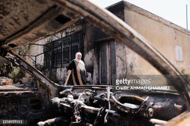 Palestinian woman carries a piece of wood as she stands outside her house, which was set on fire by Israeli settlers the day before, in Turmus Ayya...