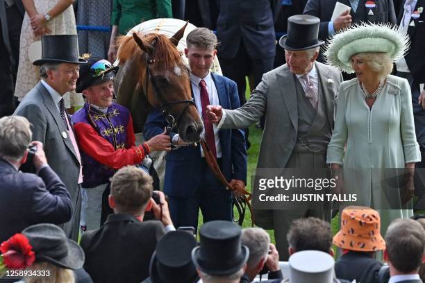 Britain's Queen Camilla and Britain's King Charles III , stable lad Jack Abbey , jockey Tom Marquand and trainer William Haggas pose in the winner's...