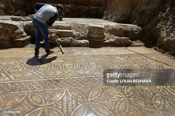 Man mops a newly unearthed scene, in an area covered in mosaic that was discovered in October 2022, in the city of al-Rastan in Syria's west-central...