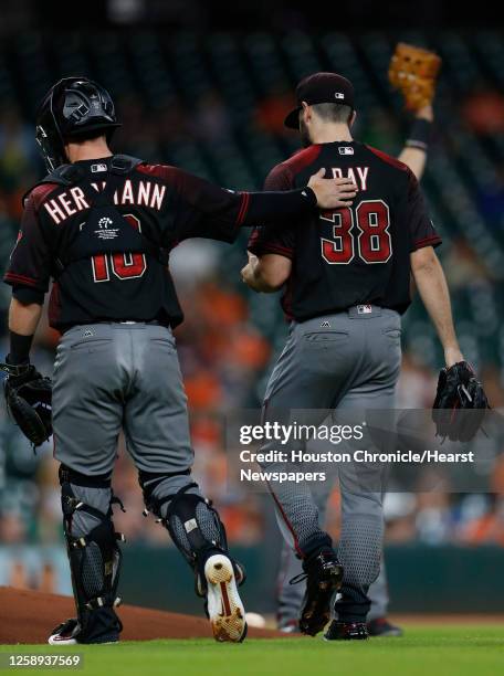 Arizona Diamondbacks starting pitcher Robbie Ray gets checked out by catcher Chris Herrmann after getting hit by a piece of George Springer's broken...