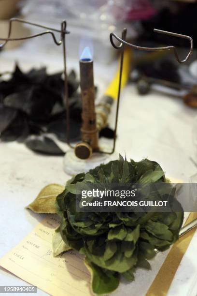 Blowtorch used to heat the moulding tools is seen behind an artificial flower in the Parisian studio of French Marcelle Guillet's manufacture in...