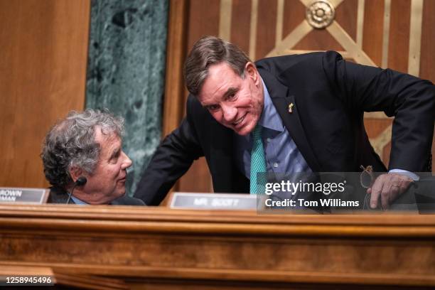 Chairman Sherrod Brown, D-Ohio, left, and Sen. Mark Warner, D-Va., are seen as Federal Reserve Chairman Jerome Powell testified during the Senate...