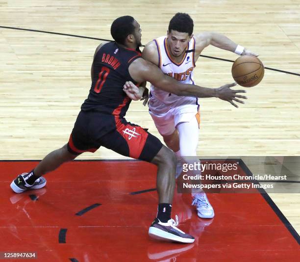 Phoenix Suns guard Devin Booker works around Houston Rockets forward Sterling Brown during the fourth quarter of an NBA basketball game at Toyota...