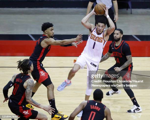 Phoenix Suns guard Devin Booker passes the ball against Houston Rockets forwards Kenyon Martin Jr. And D.J. Wilson during the third quarter of an NBA...