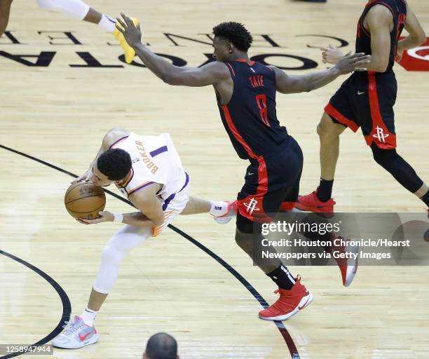 Houston Rockets forward Jae'Sean Tate fouls Phoenix Suns guard Devin Booker during the fourth quarter of an NBA basketball game at Toyota Center,...