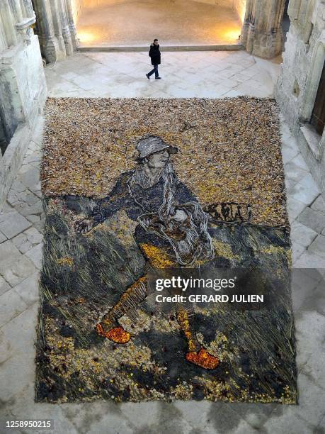 Man walks past a creation representing "The sower" of Vincent Van Gogh made by Brazilian artist Vik Muniz with branches, leaves and dried flowers,...