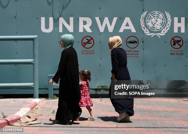 Palestinian women walk in front of the headquarters of the United Nations Relief and Works Agency for Palestine Refugees during a protest against the...