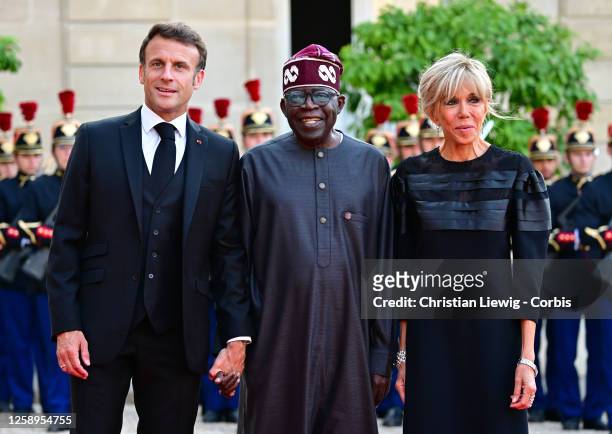 French President Emmanuel Macron and his wife Brigitte Macron greet Nigerian President President Bola Tinubu upon arrival for an official dinner at...