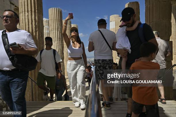 Tourists walk through Propylaia, the ancient gate as they visit the Acropolis archaeological site in Athens on June 14, 2023. "The wait and the...