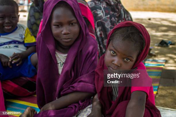 Girls sit outside at a camp for the internally displaced in al-Suwar, about 15 kilometres north of Wad Madani, on June 22, 2023. The fighting in...