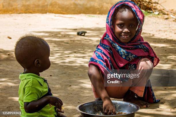 Girl eats outside at a camp for the internally displaced in al-Suwar, about 15 kilometres north of Wad Madani, on June 22, 2023. The fighting in...