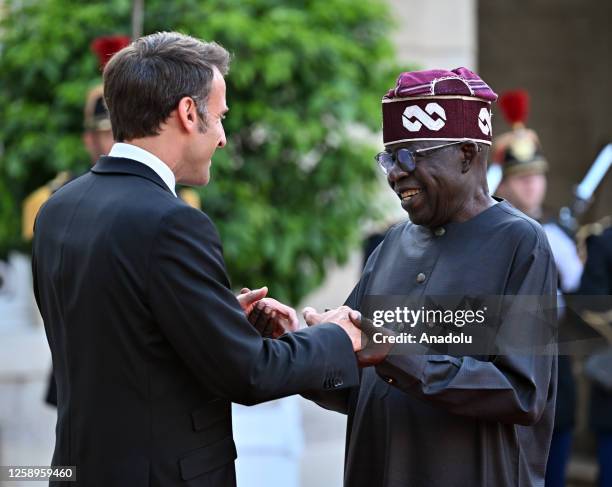 French President Emmanuel Macron greets Nigeria's President Bola Tinubu upon arrival for an official dinner at the Elysee Palace, on the sidelines of...