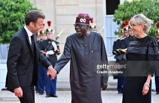 French President Emmanuel Macron and his wife Brigitte Macron greet Nigeria's President Bola Tinubu upon arrival for an official dinner at the Elysee...