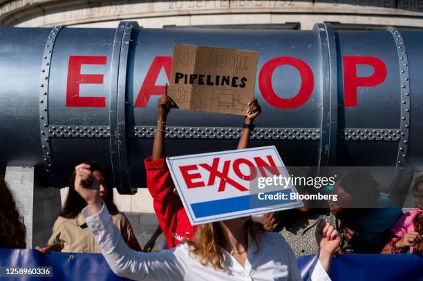 Climate activists holds an Exxon Mobil Corp. Logo during a protest against the East African Crude Oil Pipeline project on the sidelines of the Global...