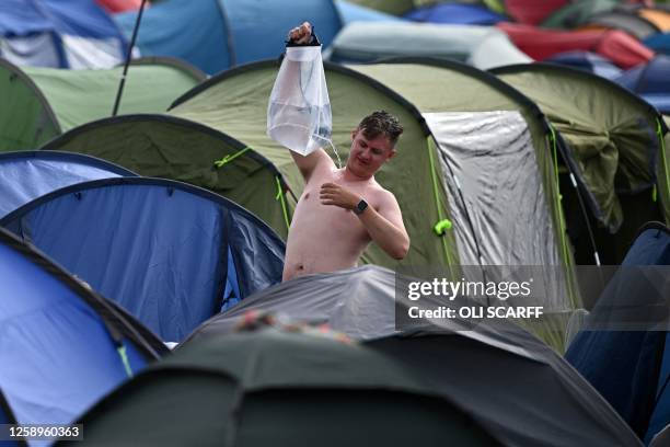 Festivalgoer uses a home-made shower early in the morning on day 3 of the Glastonbury festival in the village of Pilton in Somerset, southwest...