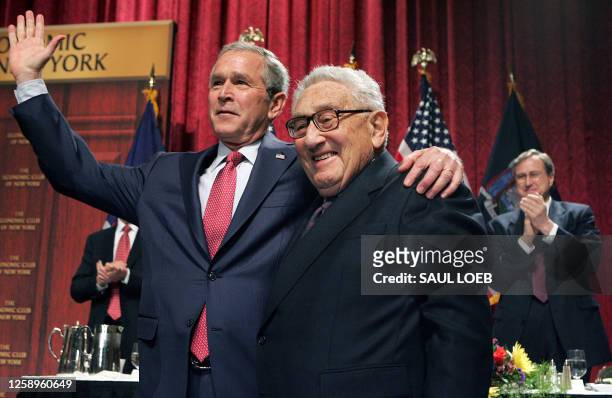 President George W. Bush waves alongside former US Secretary of State Henry Kissinger after speaking on the economy to the Economic Club of New York...