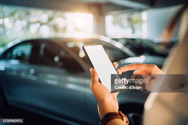 over the shoulder view of businesswoman using smartphone on the go while walking to her car in the car park in city - mobile app car stock pictures, royalty-free photos & images
