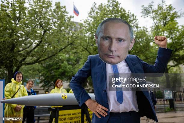 An activist wearing a mask of Russia's President Vladimir Putin stands next to fellow activists of the IPPNW peace organisation posing behind a...
