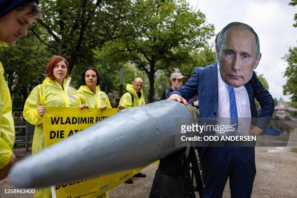 An activist wearing a mask of Russia's President Vladimir Putin stands next to fellow activists of the IPPNW peace organisation posing behind a...