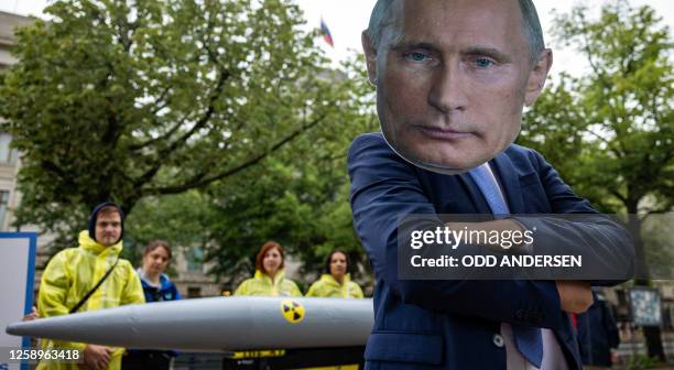 An activist wearing a mask of Russia's President Vladimir Putin stands next to fellow activists of the IPPNW peace organisation posing behind a...