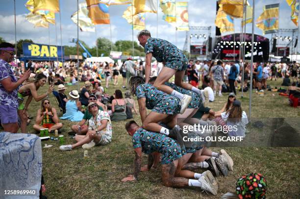 Festivalgoers build a human pyramid on day 3 of the Glastonbury festival in the village of Pilton in Somerset, southwest England, on June 23, 2023....