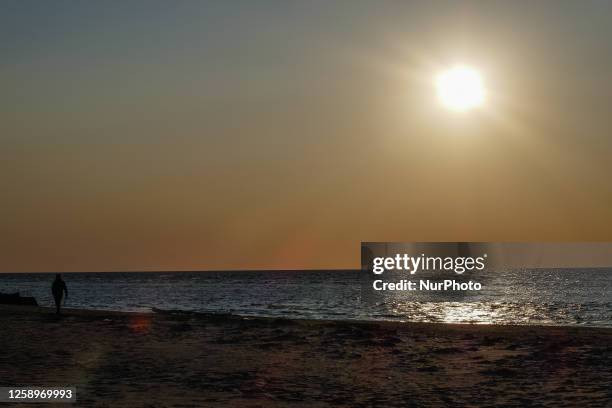 People looking at the sunset on the Baltic Sea sandy beach are seen on the Cape Kolka, Latvia on 9 June 2023