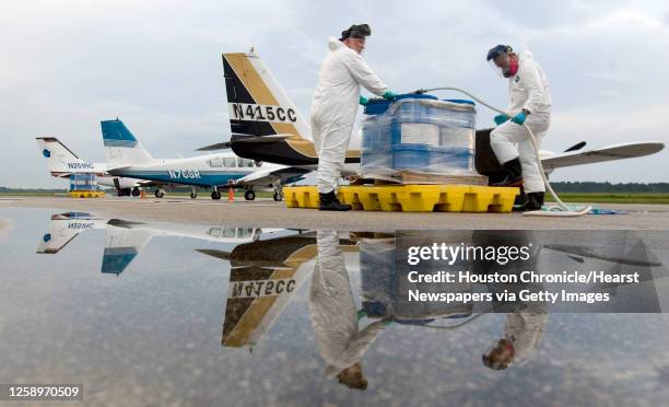 Charles Speights , left, and Terry Shive , of ADAPCO Vector Control Services, load pesticide onto one of four airplanes at Hooks Airport as they...