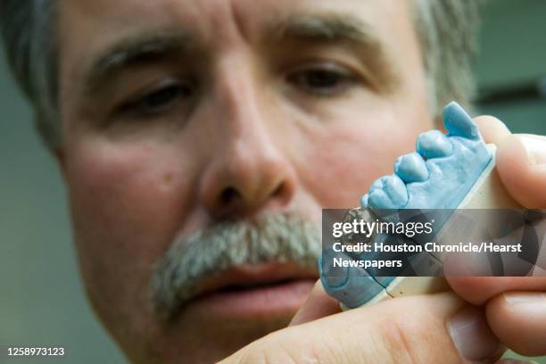 Stephen Spoon, owner of Miracle Dental Lab, inspects a finished gold tooth at the lab Wednesday, July 16 in Houston. Spoon said he inspects every...