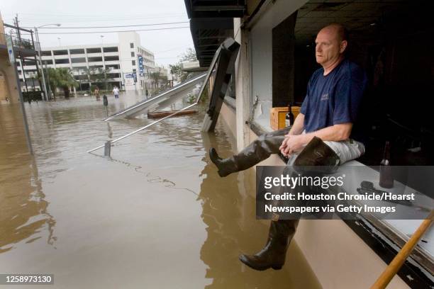 Brian Merrell sits on the window ledge of Rudy and Paco Restaurant keeping watch over the business that lost it windows and was flooded in the...